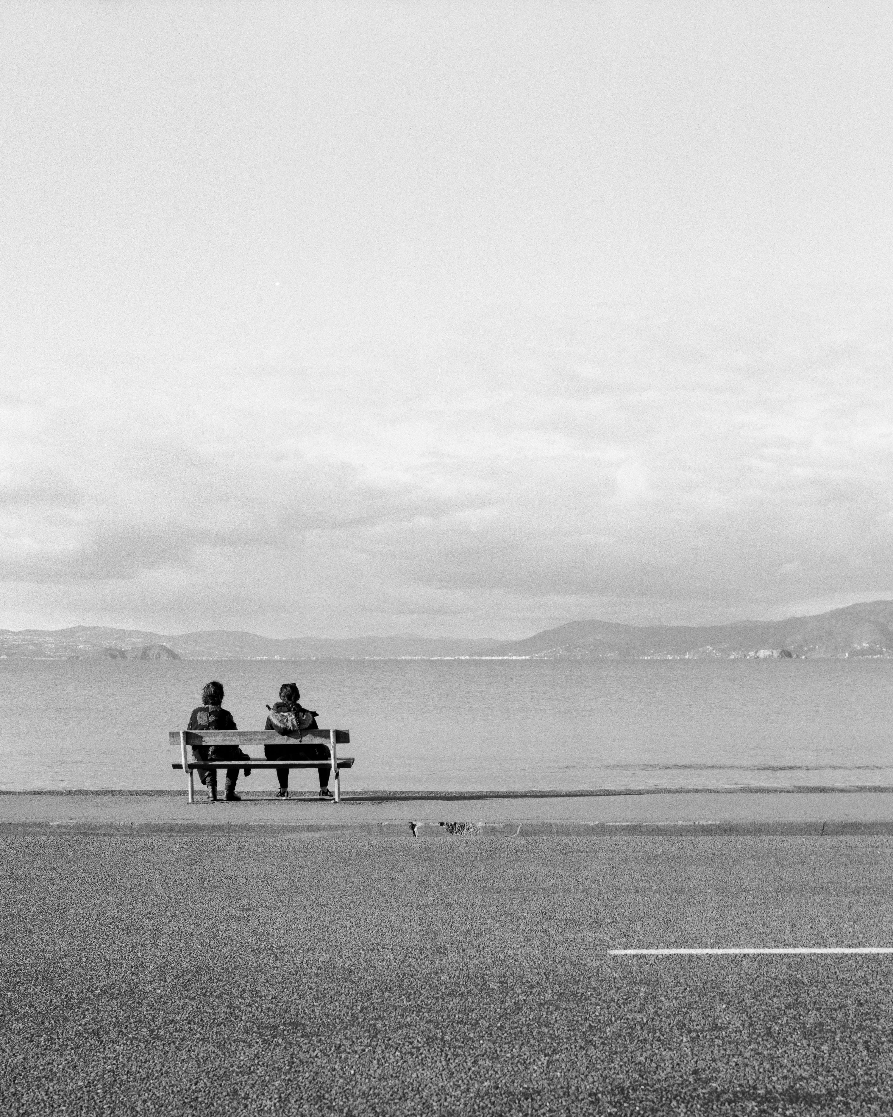 Photo of two people on a bench by the waterside 