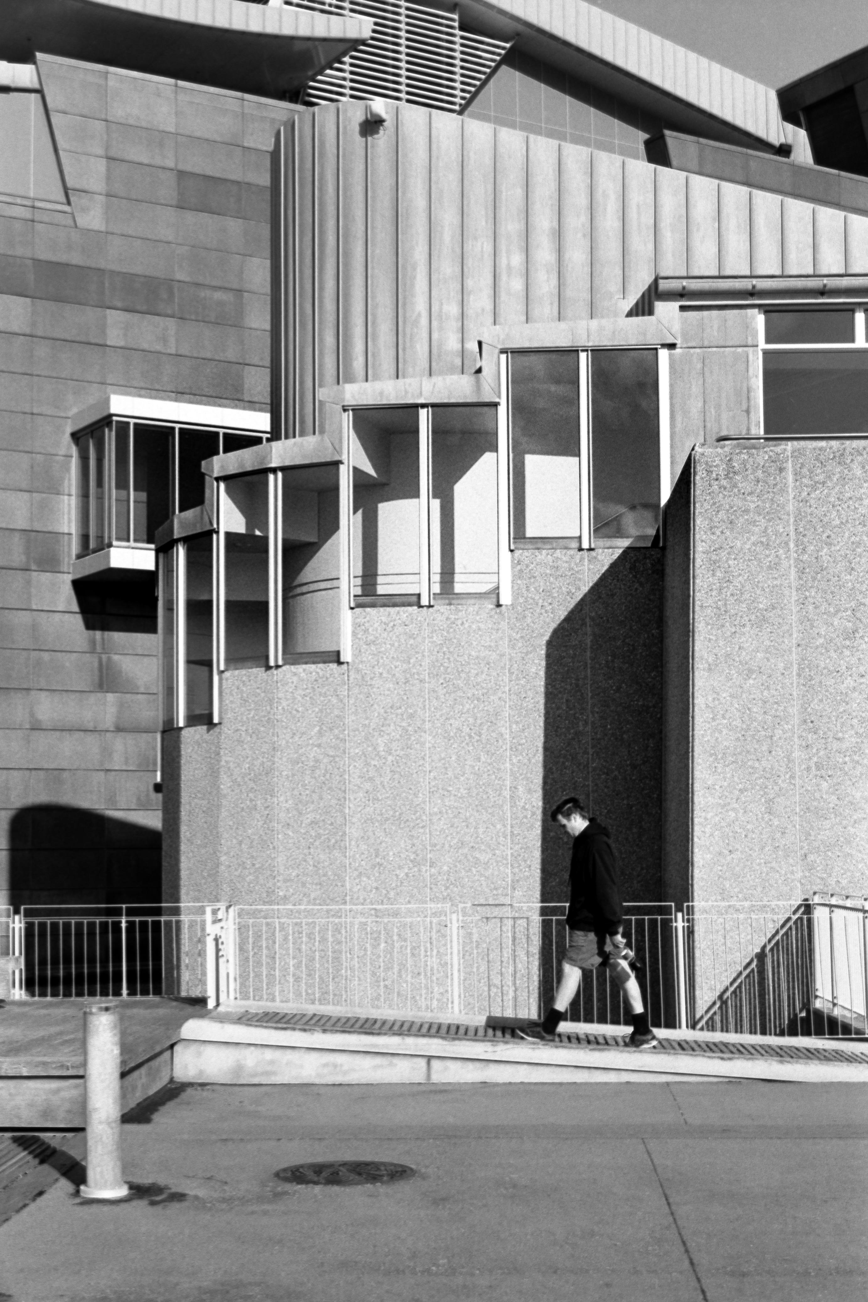 Photo of a man walking past a museum wall
