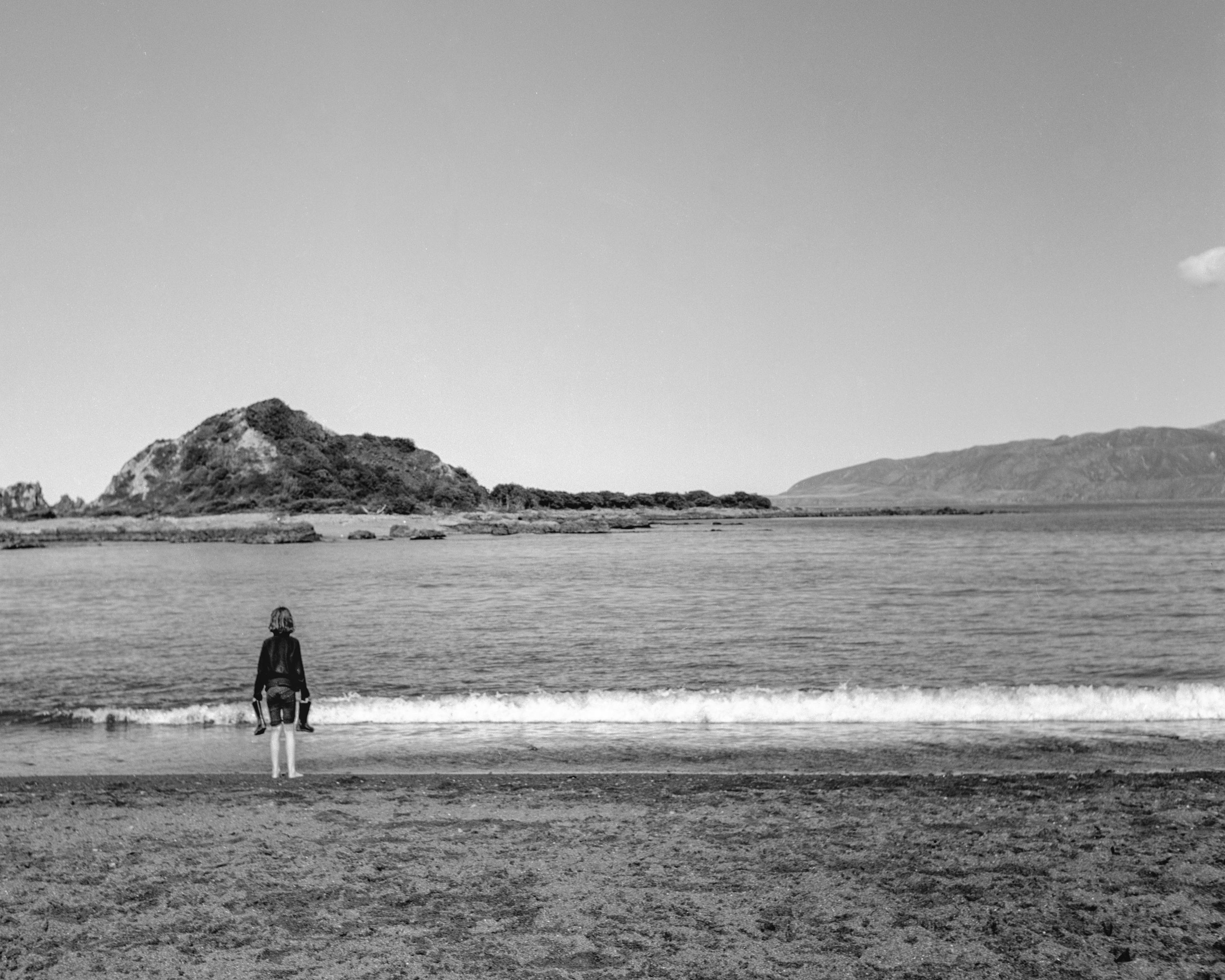 Photo of a child standing at the sea shore 
