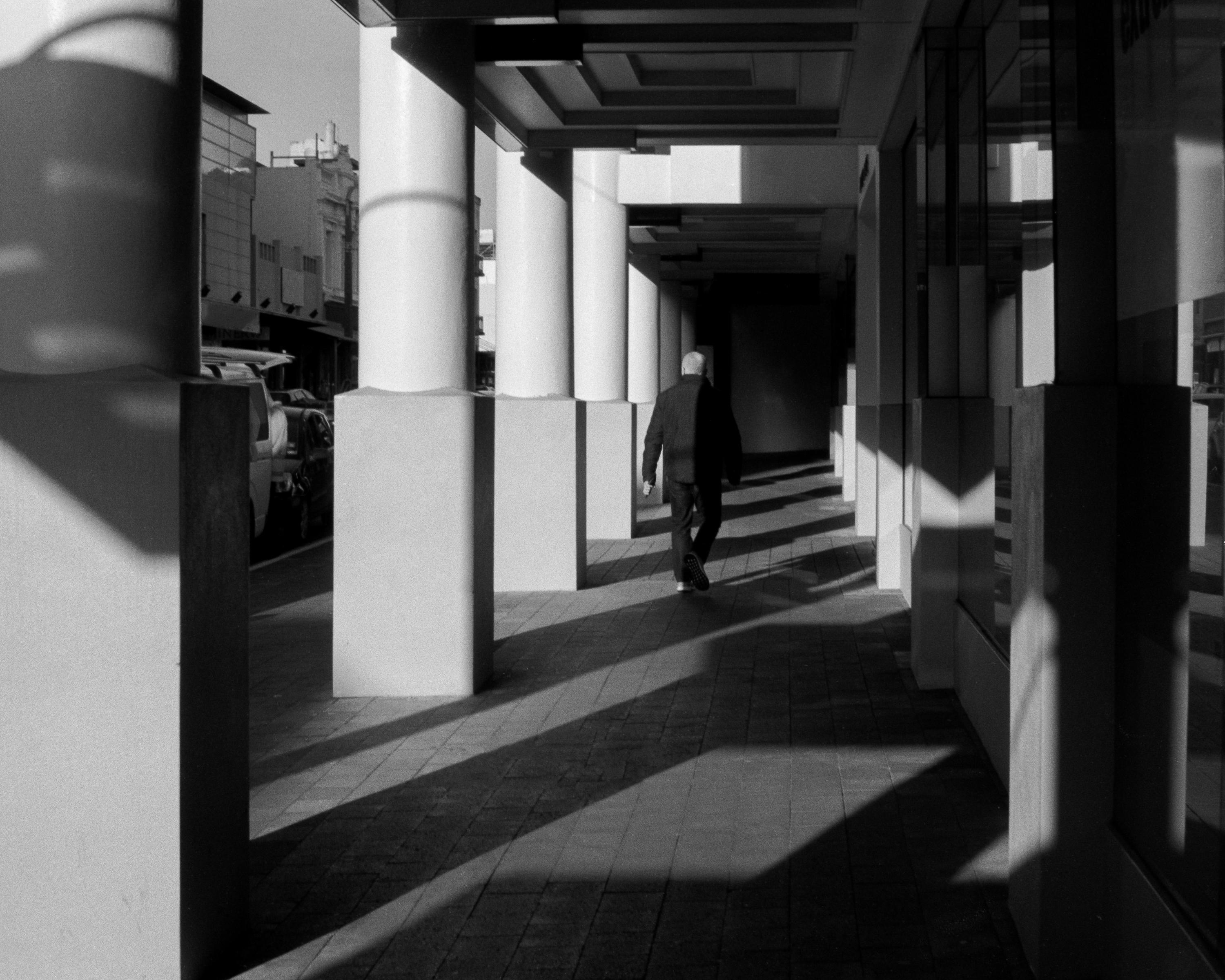 Photo of a man walking down a large open corridor 