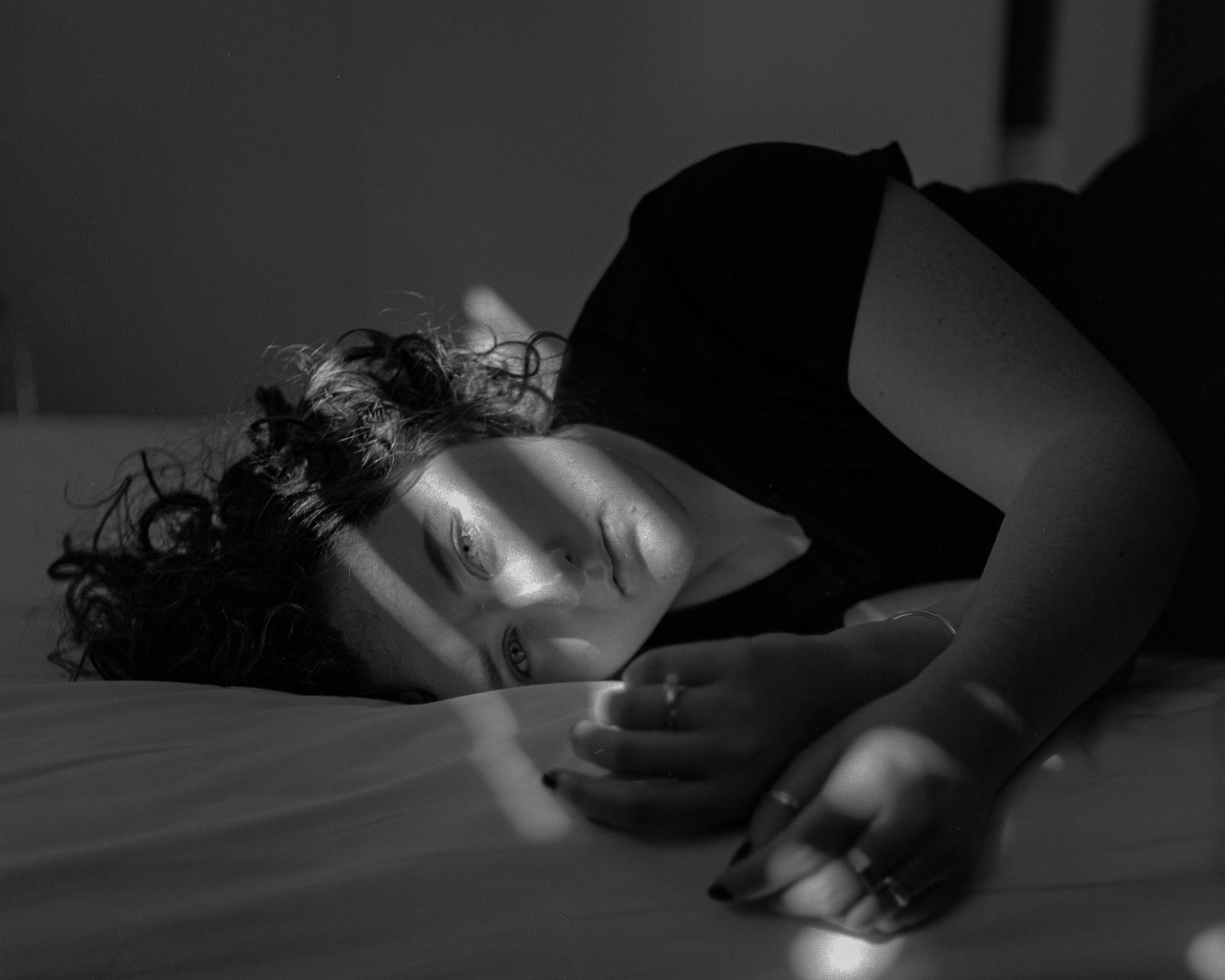Photo of a woman lying in bed in dim light