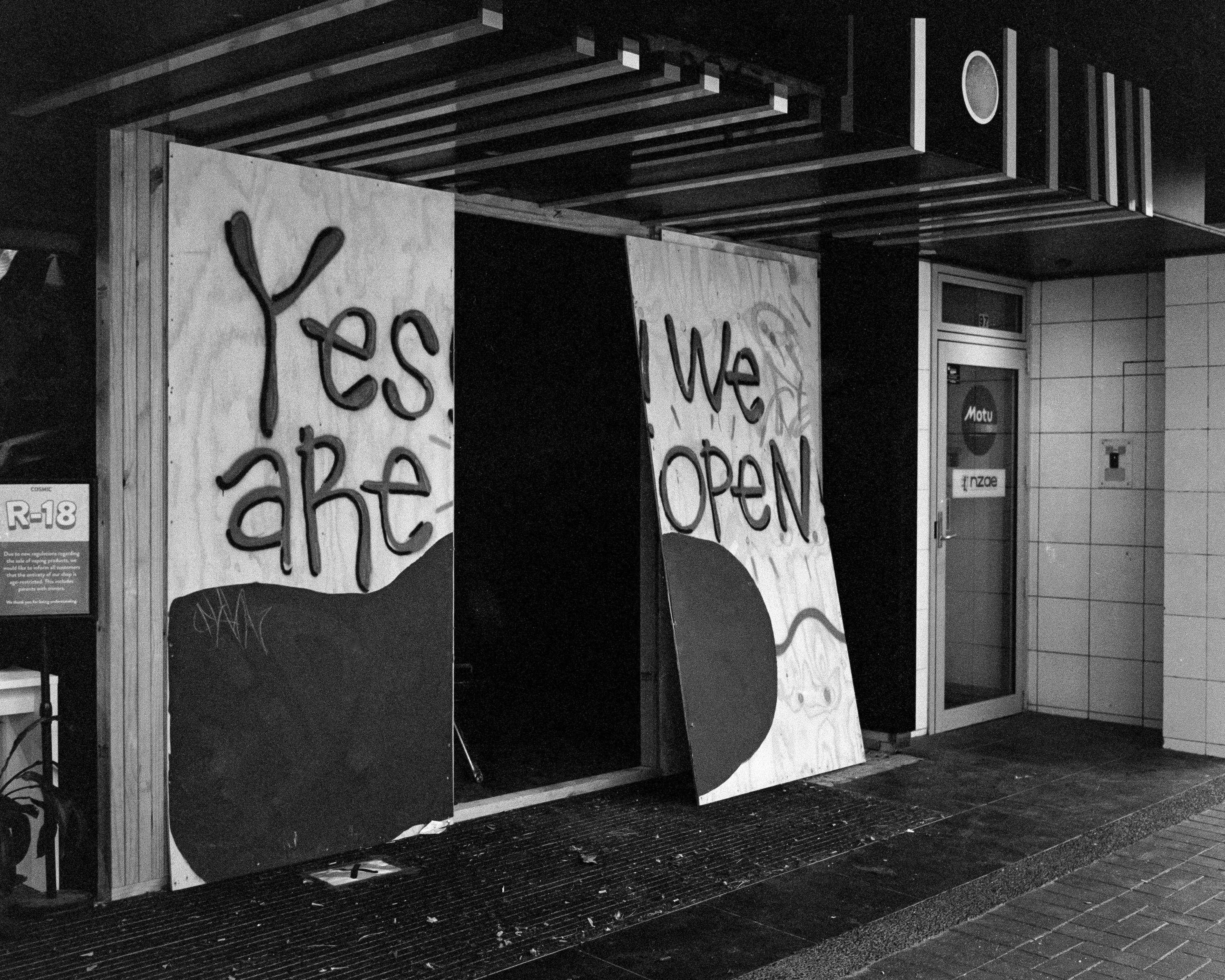 Photo of a storefront with large wooden boards covering it 