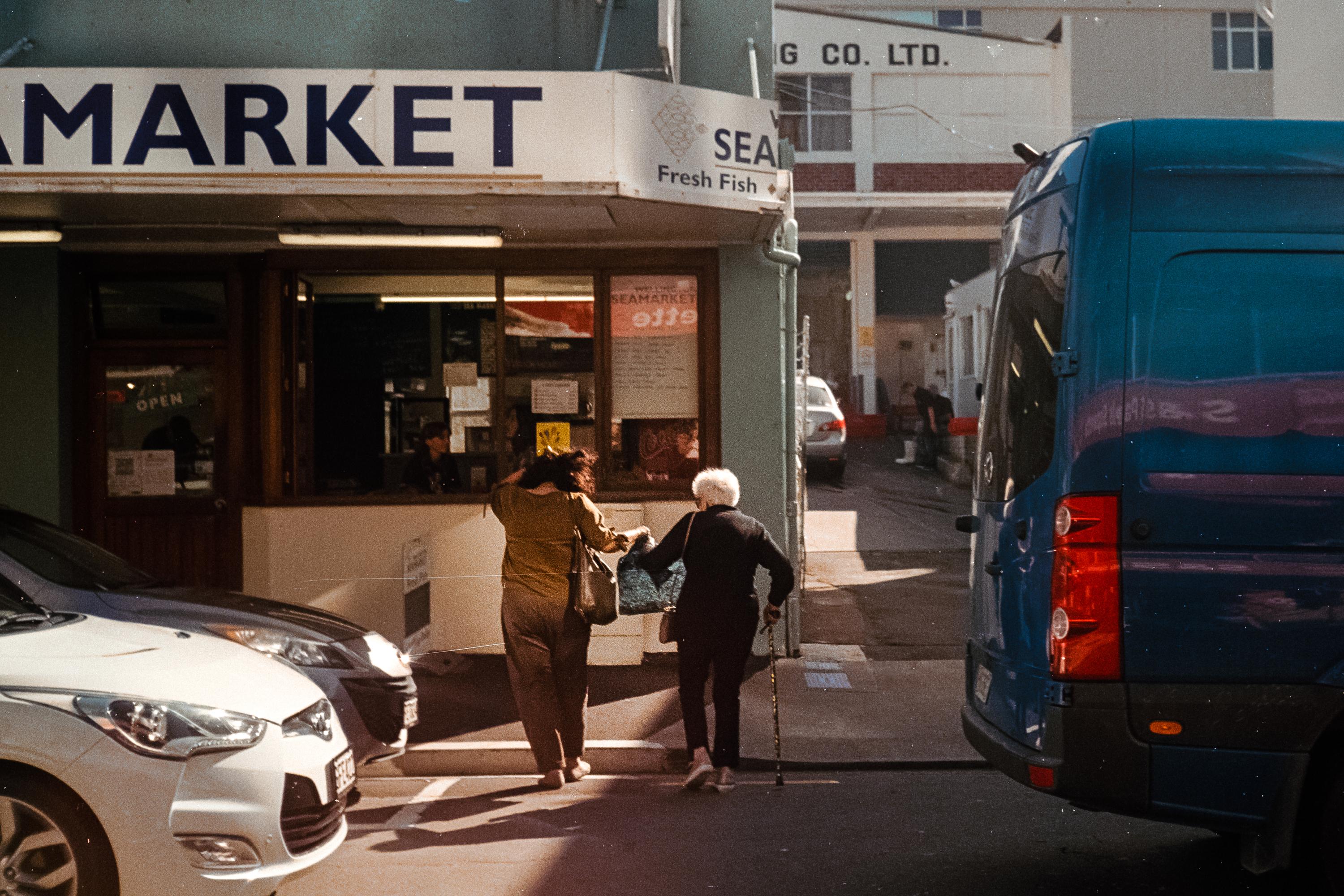 Photo of elderly mother and daughter walking across the street 