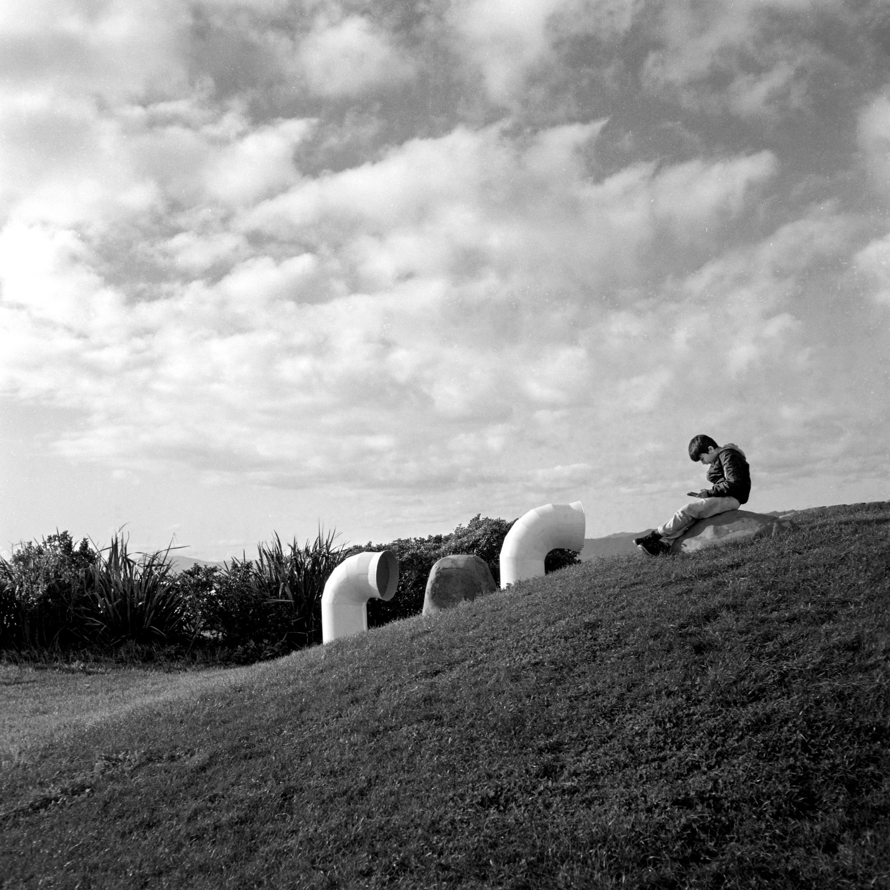 Photo of a small boy sitting on a hill 