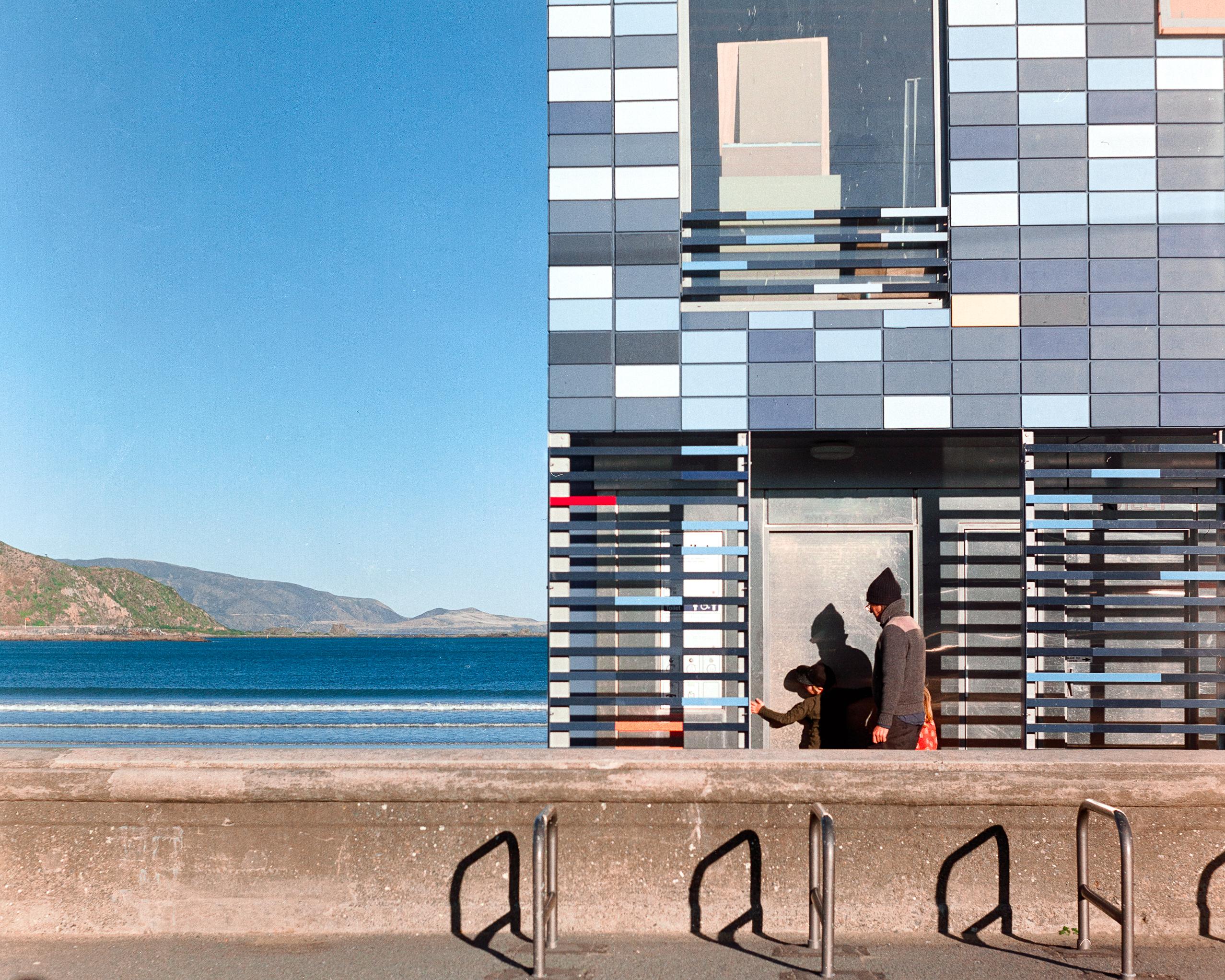 Photo of a man entering a blue building on the sea shore 