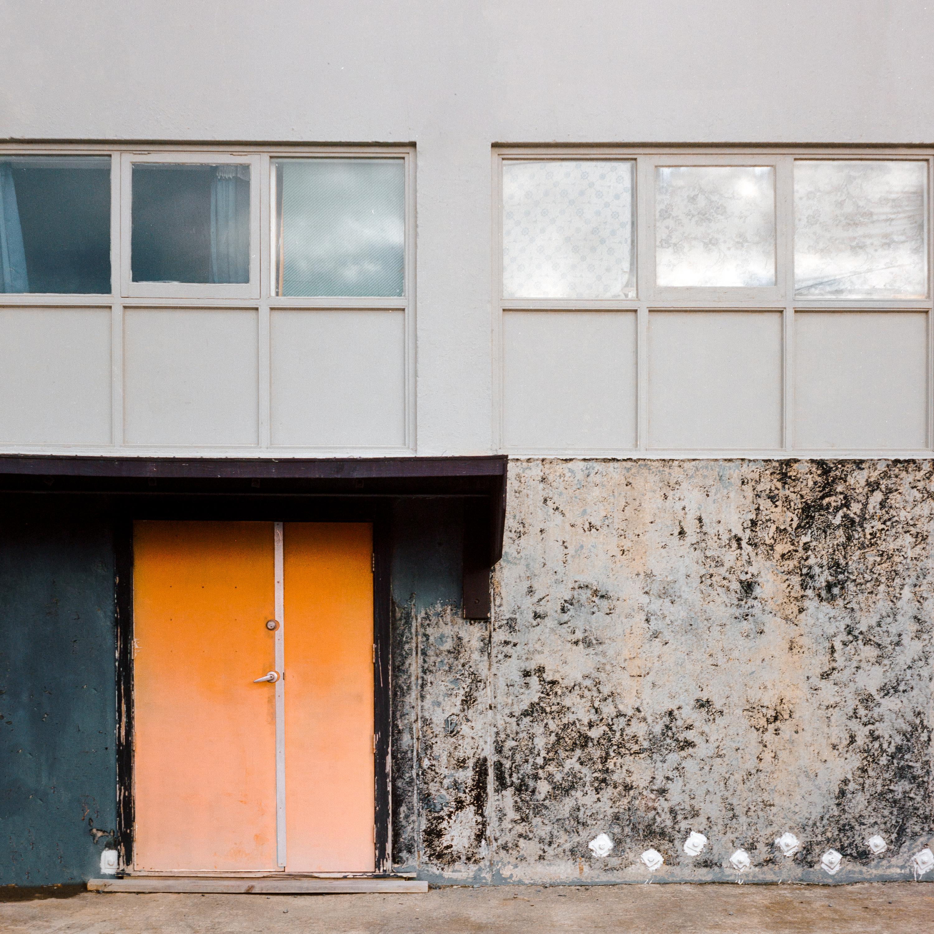 Photo of a building facade with an orange door 